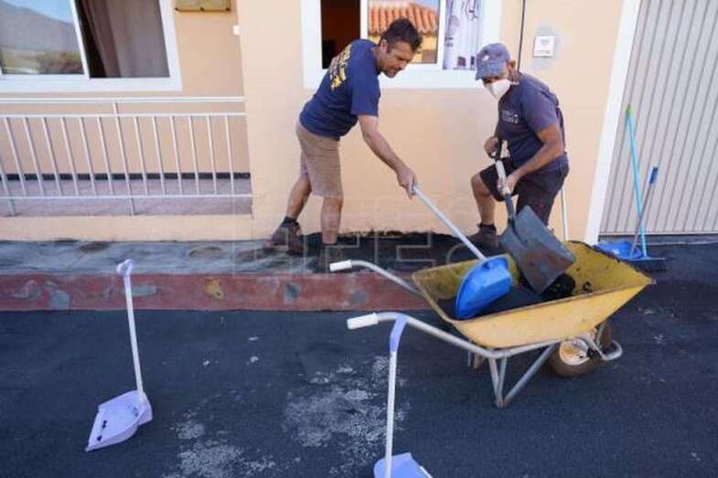 Dos hombres limpian de ceniza volcánica el frente de su casa en el municipio palmero de Tazacorte, en una imagen de archivo / EFE Ramón de La Rocha